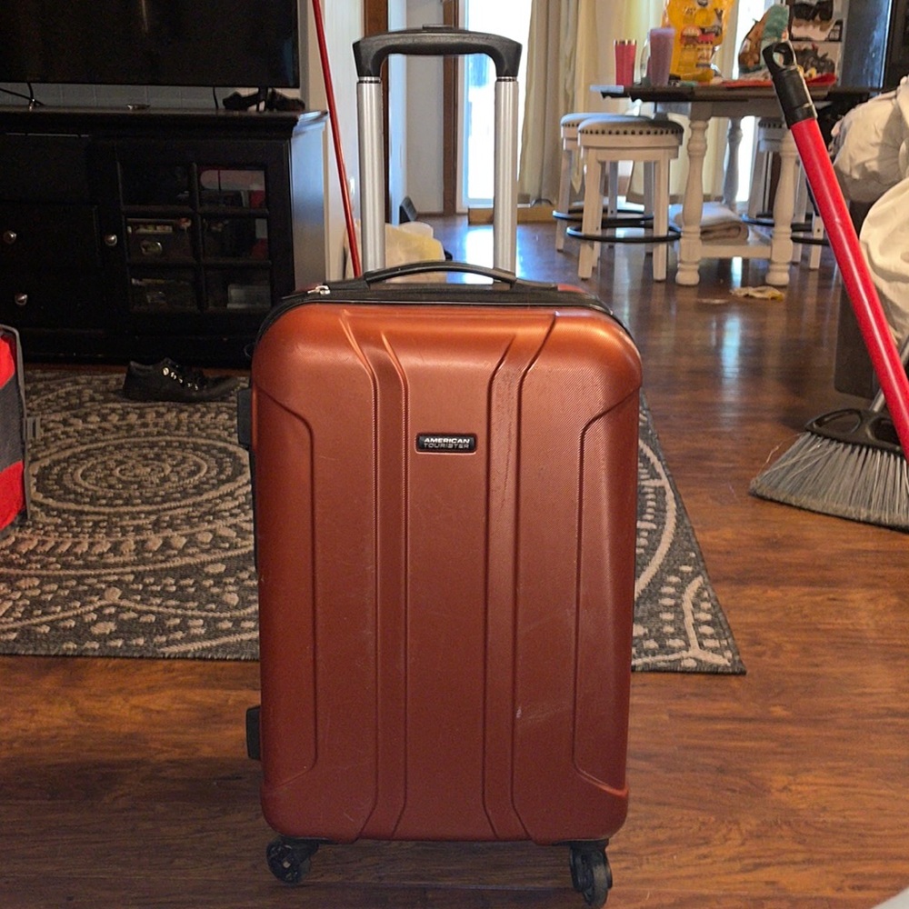 Orange four wheel heavy duty suitcase made by American Tourister